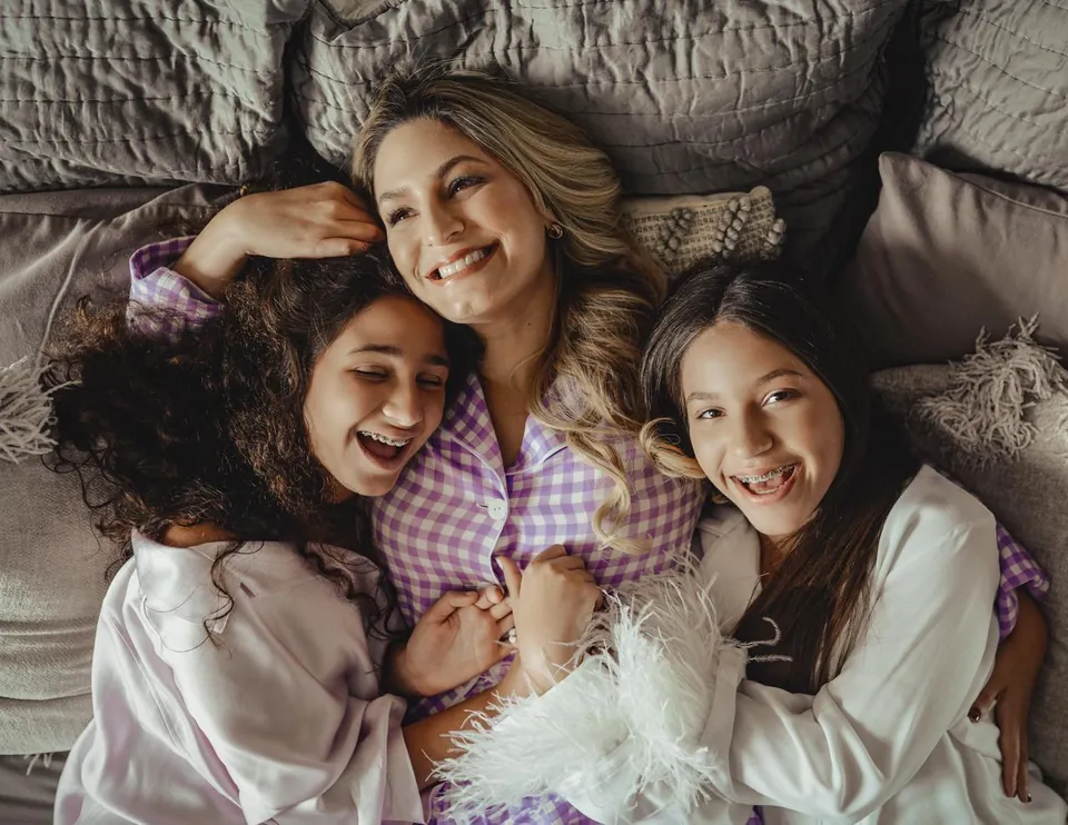 Miriam ríe recostada con sus dos hijas